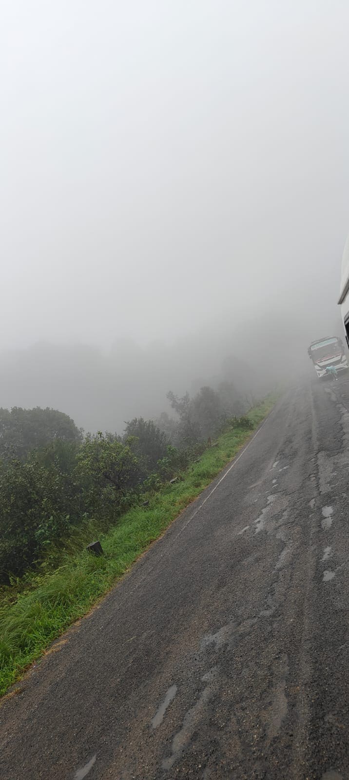 Thick fog covering a ghat road with a bus ahead